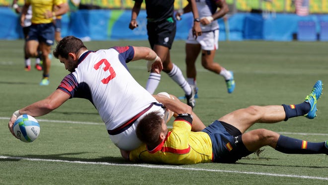 Danny Barrett of the United States puts the ball down for a try as he is tackled by Marcos Poggi of Spain during a rugby sevens match between at Deodoro Stadium in the Rio 2016 Summer Olympic Games.