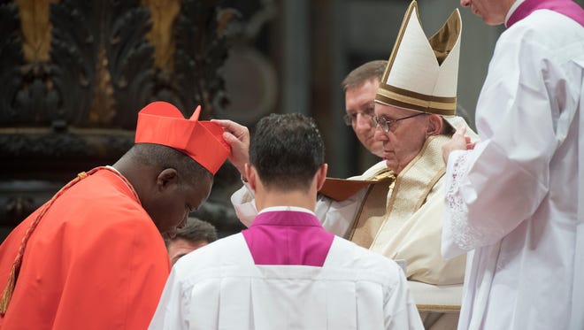 Archbishop of Bangui, Dieudonne Nzapalainga, left, kneels before Pope Francis to pledge allegiance and become cardinal, on Nov. 19, 2016 during a consistory at Peter's basilica. Pope Francis has named 17 new cardinals, 13 of them under age 80 and thus eligible to vote in a conclave to elect his successor.