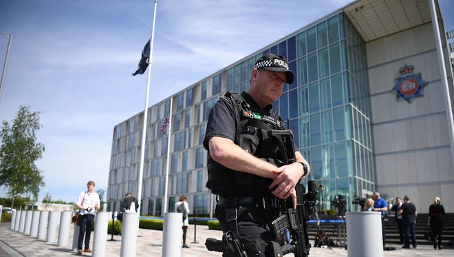 Armed police guard Greater Manchester Police station as a flag flies at half-staff in the background on May 23, 2017, in Manchester, England.