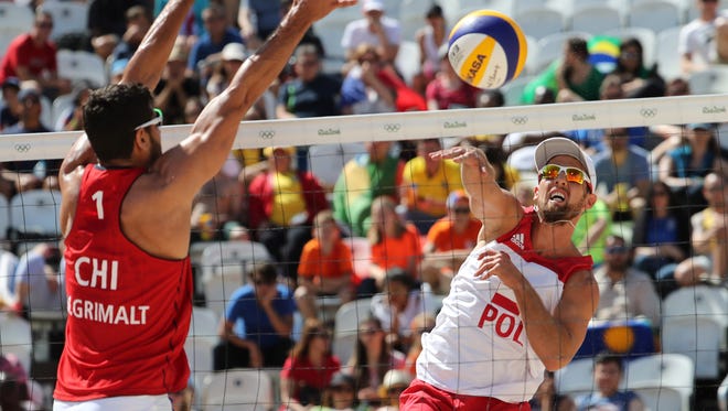 Grzegorz Fualek of Poland hits a shot against against the block Marco Grimalt  of Chile in a men's preliminary - Pool E match at the Beach Volleyball Arena during the Rio 2016 Summer Olympic Games.