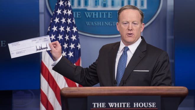 Spicer displays the first-quarter check of Trump's salary, which he donated to the National Park Service, during the daily press briefing at the White House on April 3, 2017.