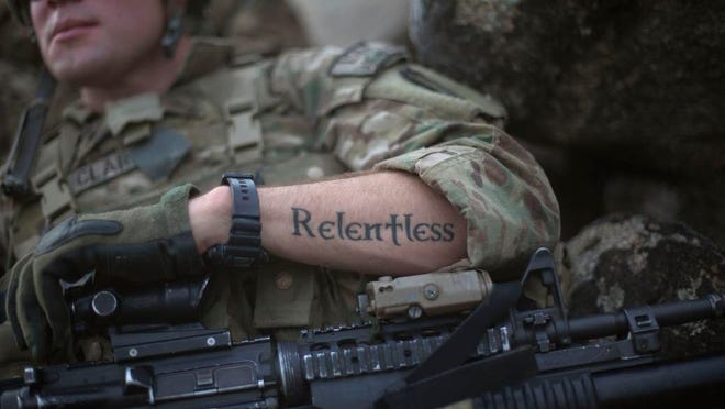 A tattoo reading “relentless” decorates the arm of Pfc. Mitchell Clark, 22, of Crestview, Fla., with the U.S. Army’s Bravo Company of the 25th Infantry Division, 3rd Brigade Combat Team, 2nd Battalion 27th Infantry Regiment based in Schofield Barracks, Hawaii, as he holds a security position during a patrol in 2011 outside the village of Jaj in Kunar province, Afghanistan.