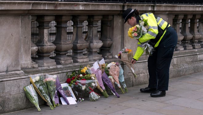 A police officer lays down flowers from members of the public in London on March 23, 2017.