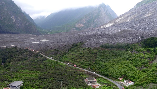 Vehicles and people line a road leading to the site of a landslide in Xinmo village in Maoxian County in southwestern China's Sichuan Province, Saturday. Dozens of people are feared buried by a landslide that unleashed huge rocks and a mass of earth that crashed into their homes in southwestern China early Saturday, a county government said.