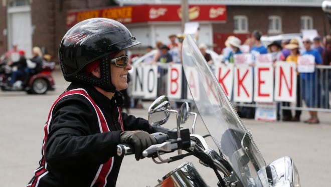 Sen. Joni Ernst parks her bike as protesters of the Bakken pipeline demonstrate behind her Saturday, Aug. 27, 2016, during the second annual Roast and Ride at the Iowa State Fairgrounds in Des Moines.