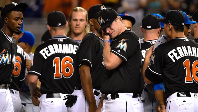 Marlins starting pitcher Tom Koehler, middle, wipes tears away after greeting the Mets at the pitchers mound.
