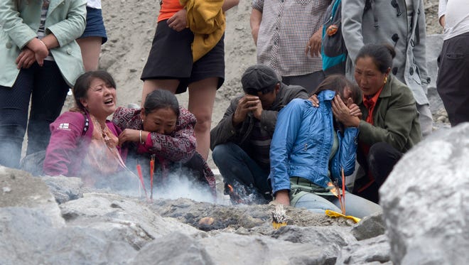 Rescue workers wait as heavy machinery clears dirt at the site of a landslide in Xinmo village in Maoxian County in southwestern China's Sichuan Province on Sunday, June 25, 2017.