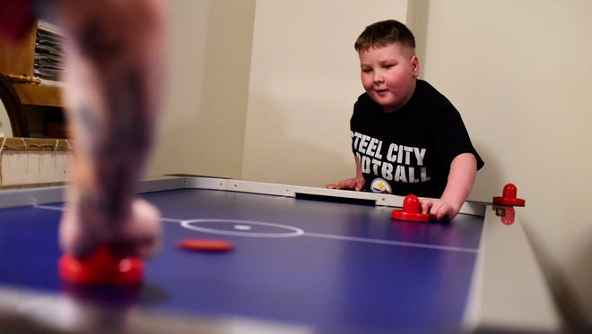 Ayden Zeigler-Kohler plays air hockey at home toward the end of February. Though his balance and motor skills were deteriorated from two cancerous tumors, Ayden was able to keep himself upright by using the wall behind him to balance.