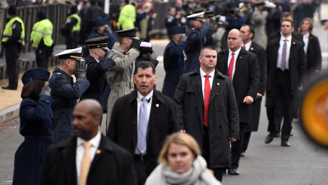 Secret Service agents walk the parade route as President Donald J. Trump's motorcade moves along.