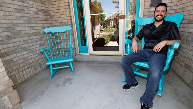 Danny Aguilar takes a seat in one of the rocking chair on the front porch of his home in Lakewood, Colo. Aguilar, like nearly half of Americans surveyed in a new poll conducted by The Associated Press-NORC Center Public Affairs Research, said they will not be taking a vacation this summer because they can not afford it or can not get time away from the job.