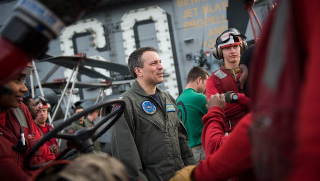 Commanding Officer of the USS Dwight D. Eisenhower, U.S. Navy Capt. Paul C. Spedero, an experienced naval aviator who flew combat missions in support of Operation Iraqi Freedom and Operation Enduring Freedom, on the flight deck talking with red shirted emergency and ordnance crew members.