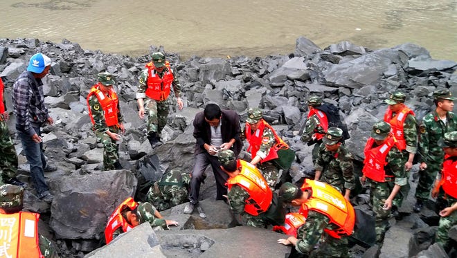 Emergency personnel and locals work at the site of a landslide in Xinmo village in Sichuan Province.