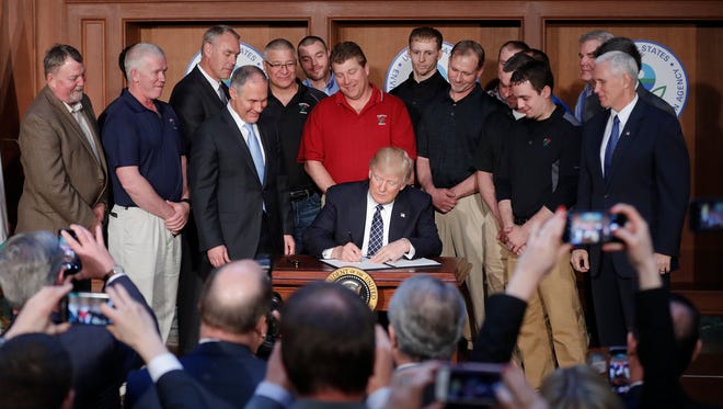 President Trump, accompanied by Environmental Protection Agency Administrator Scott Pruitt, Vice President Mike Pence and a dozen coal miners, signs an executive order on energy independence Tuesday at EPA headquarters in Washington.