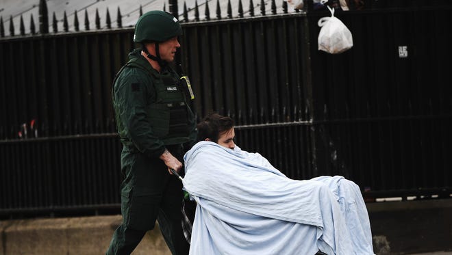 A member of the public is taken away for treatment by emergency services medic near Westminster Bridge and the Houses of Parliament in London.