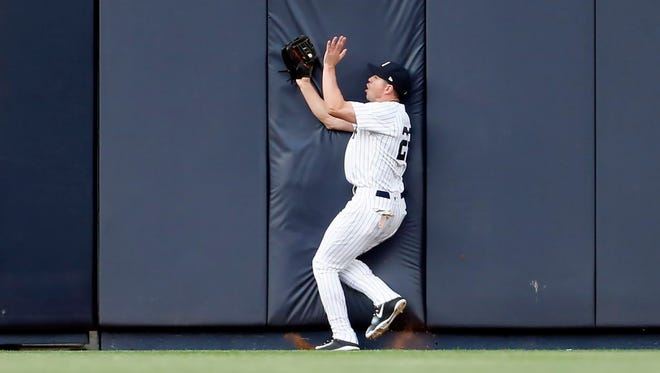 New York Yankees center fielder Jacoby Ellsbury (22) makes a catch while running into the outfield wall against the Kansas City Royals during the first inning at Yankee Stadium.