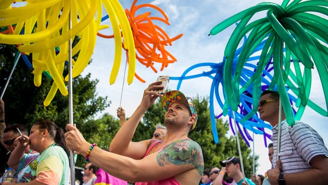 David Westover, of Nashville, takes a picture with his phone while holding balloons during the Nashville Pride Equality Walk in downtown Nashville, Tenn., Saturday, June 24, 2017.