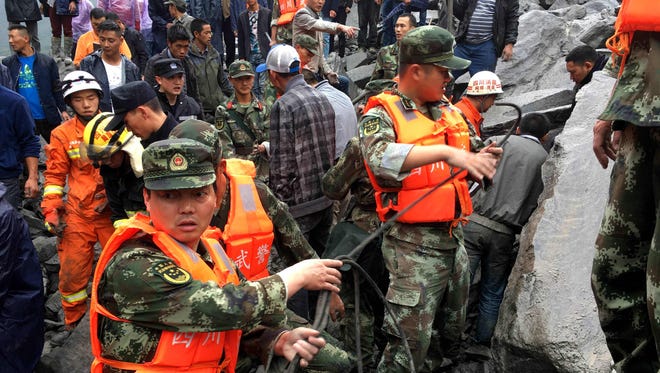 Chinese military police and rescue workers are seen at the site of a landslide in in Xinmo village, Diexi town of Maoxian county. Around 100 people are feared buried after a landslide smashed through their village in southwest China's Sichuan Province early Saturday, local officials said, as they launched an emergency rescue operation.