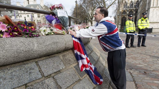 A man places a floral tribute near a police cordon in Westminster in central London on March 23, 2017.
