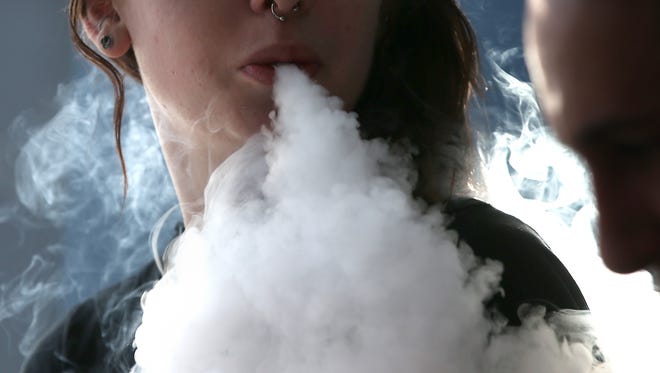 A young woman smokes an e-cigarette in San Rafael,  California.