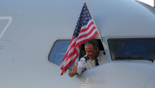 An American Airlines pilot gives a thumbs-up under the U.S. flag as the first regular flight from the USA to Havana arrives on Nov. 28, 2016.