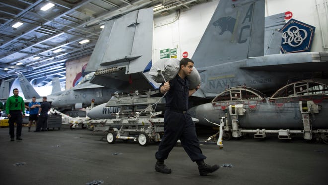 USS Eisenhower crew members carry supplies on the hangar deck during a coordinated ship-to-ship resupply mission.