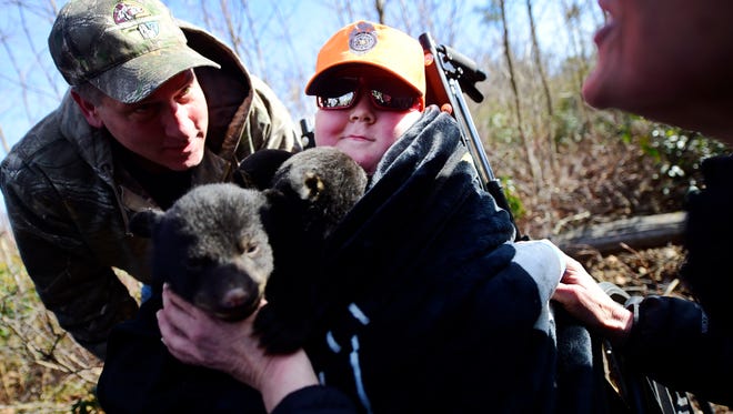 Ayden Zeigler-Kohler, 10, smiles as he cuddles with three bear cubs in the Sproul State Forrest in Noyse Township in March. Ayden and his father, Bill Kohler, left, were invited to hold the cubs who were being checked on as a part of a study by the Pennsylvania Game Commission, after a Wildlife Conservation Officer read their story.