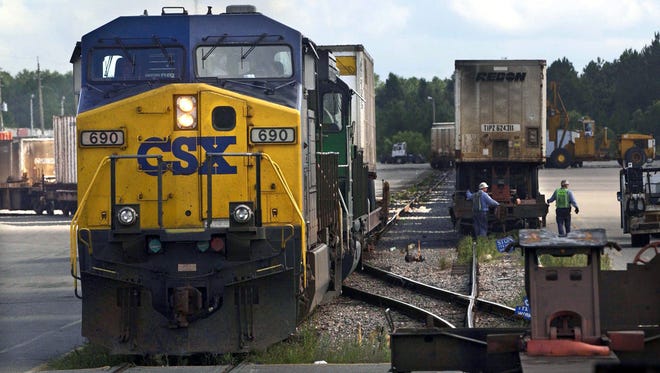 Workers repair a rail car as a train comes into the yard July 29, 2004, at CSX's Duval Yard in Jacksonville, Fla.