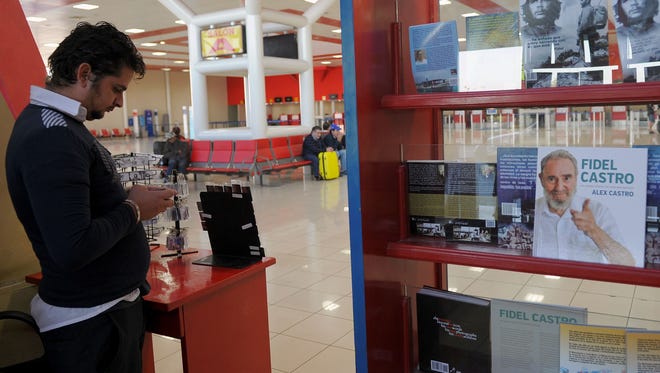 A Havana airport worker checks his cell phone next to a display of books of Cuban leader Fidel Castro and guerrilla leader Ernesto "Che" Guevara at the Havana airport on Nov. 28, 2016.