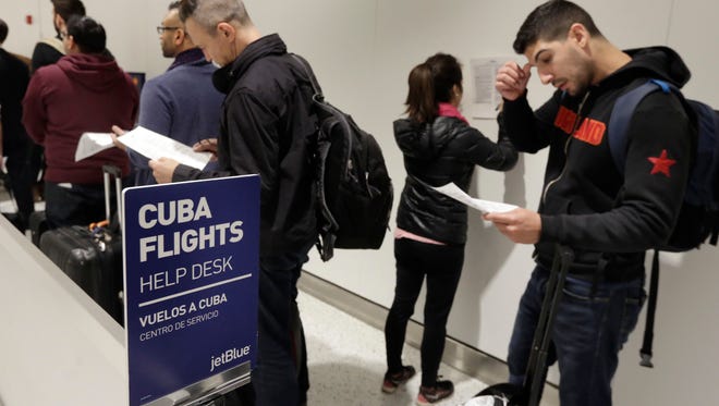Passengers look over their paperwork while waiting to check in for JetBlue's inaugural flight to Havana from JFK airport on Nov. 28, 2016.
