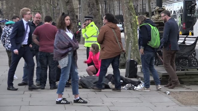 In this image from video, a girl lying on the ground is treated by passersby on the Embankment near to the Houses of Parliament in London on March 22, 2017.