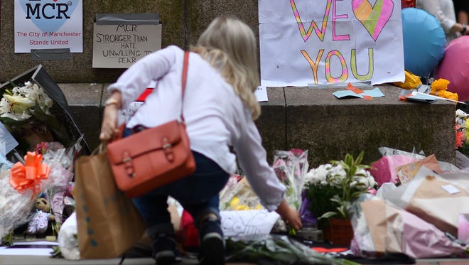 A woman places flowers beneath a sign that reads "Ariana we love you" in St Ann's Square in Manchester May 24, 2017, in tribute to the victims of the May 22 terror attack at the Manchester Arena.