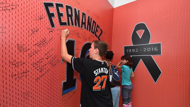 A young fan signs a wall placed outside a gate at Marlins Park.