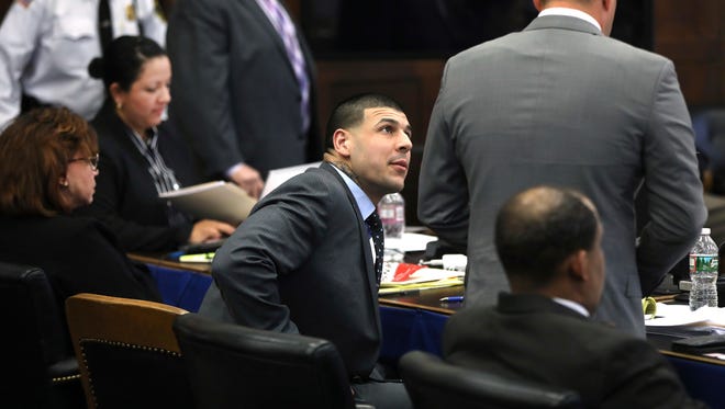 Surrounded by his defense team, Aaron Hernandez looks to attorney Jose Baez during the double murder trial of former New England Patriots tight end Hernandez in Suffolk Superior Court in Boston on Thursday, March 16, 2017. Prosecutors in Hernandez's double-murder trial have asked a judge to allow them to tell the jury he told a witness he was "very angry all the time."