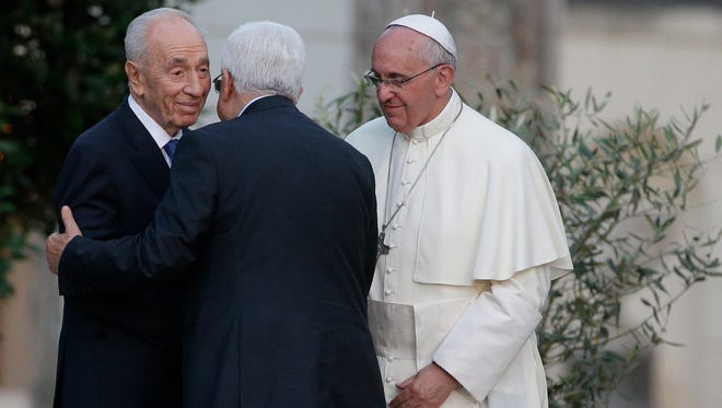 Pope Francis looks on as Israel's President Shimon Peres, left, and Palestinian President Mahmoud Abbas greet each in the Vatican gardens on Sunday.