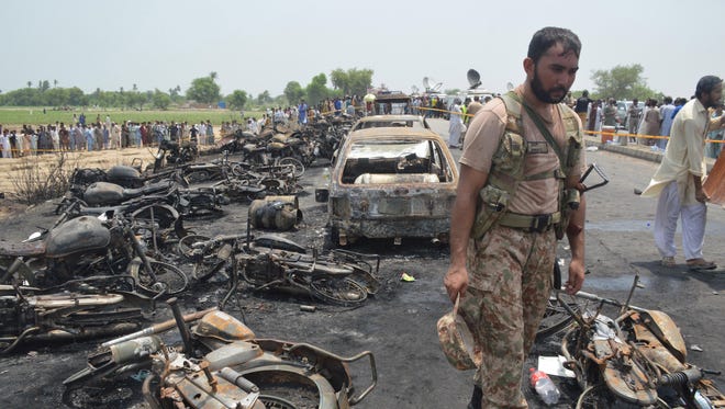A Pakistani Army soldier stands guard amid the charred vehicles at the scene of an oil tanker accident on the outskirts of Bahawalpur, Pakistan, on June 25, 2017.