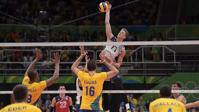 United States middle blocker Maxwell Holt hits the ball against Brazil during the men's preliminary.