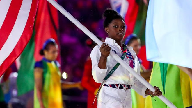 Simone Biles (USA) carries the flag during the closing ceremonies for the Rio 2016 Summer Olympic Games at Maracana.