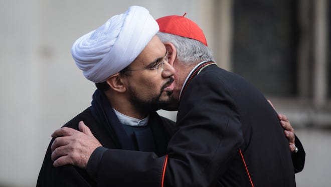 Sheikh Mohammed al Hill, left, embraces Cardinal Vincent Nichols, Archbishop of Westminster, right, following a vigil outside Westminster Abbey, Friday, in London. Faith leaders came together and held a one minute silence today following the terror attack .