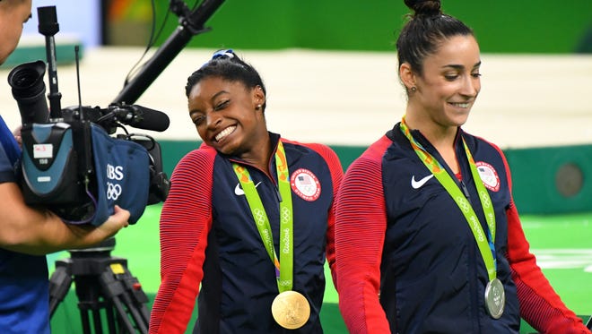 Simone Biles (USA) and Alexandra Raisman (USA) celebrates winning the gold and silver medals during the women's individual all-around final in the Rio 2016 Summer Olympic Games at Rio Olympic Arena.