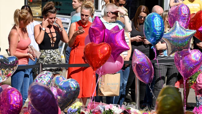Members of the public look at tributes left for the people who died in Monday's terror attack at the Manchester in England. An explosion occurred at Manchester Arena on the evening of May 22 as concert goers were leaving the venue after Ariana Grande had performed. Greater Manchester Police are treating the explosion as a terrorist attack and have confirmed 22 fatalities with many more injured.