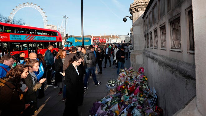 People pause at the floral tributes to the  March 22 terror attack victims.