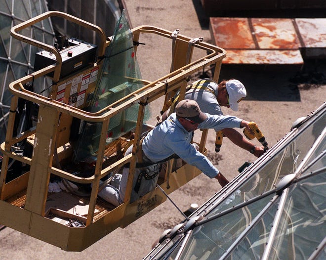 Iron workers Tom Freda and George Schroeder unscrew a triangular window that measures five to six feet from the side of a dome in September, 1998.
