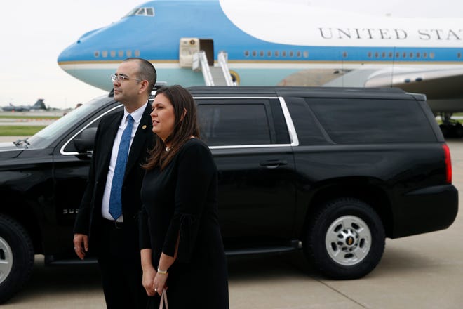 White House press secretary Sarah Huckabee Sanders, right, watches President Donald Trump greet visitors on the tarmac at Des Moines International Airport in Des Moines, Iowa, Tuesday, June 11, 2019.